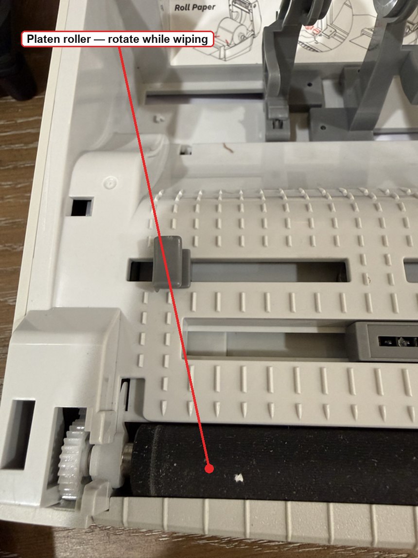 The black rubber platen roller in the base of the printer, marked to rotate it while wiping